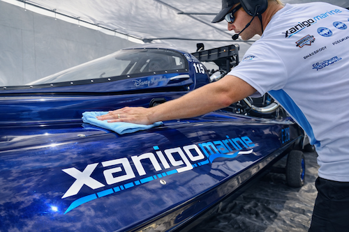Person cleaning a blue boat with Xanigo Marine' branding.